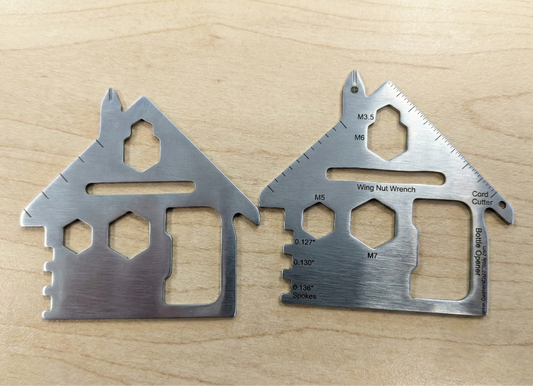 Two metallic multitools on a wooden surface. house shaped