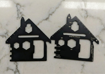 Two black multi-tool cards shaped like houses on a marble surface