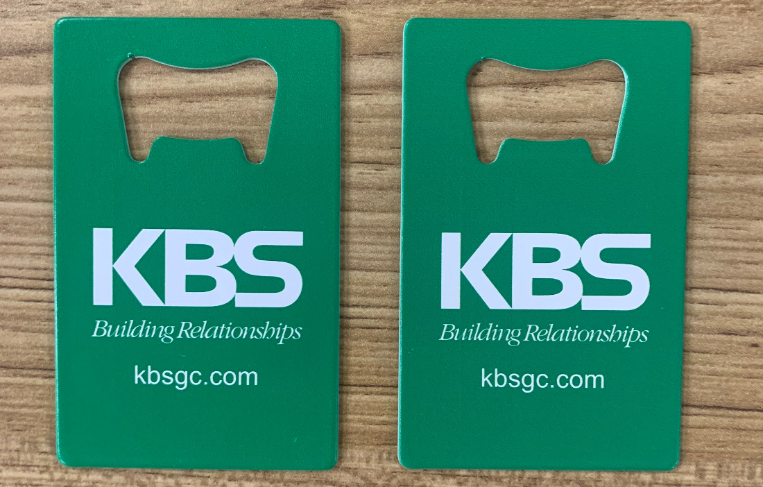 Two green KBS cards with a wooden cutout on a wooden surface