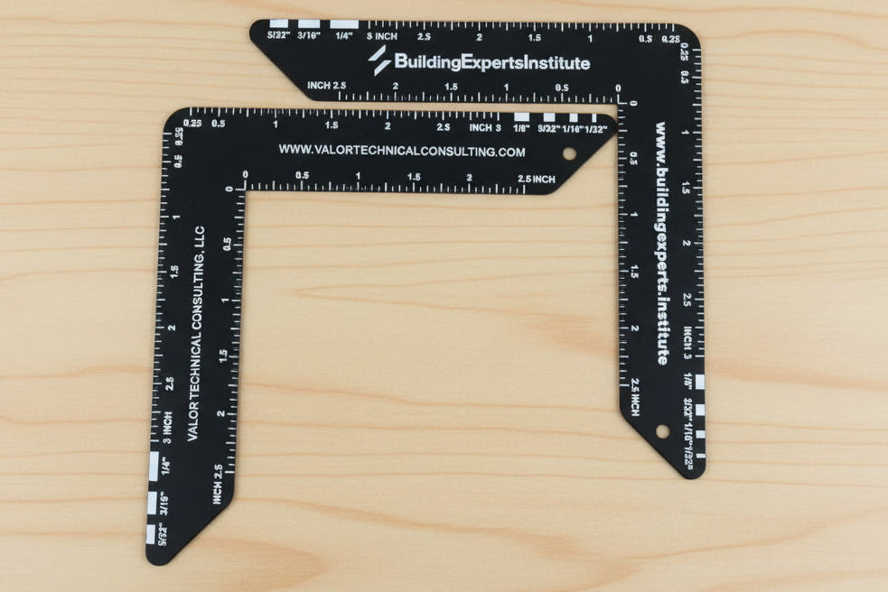 Two black triangular rulers with measurement scales on a wooden surface